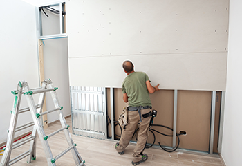 A construction worker installing a new drywall panel in a residential home.